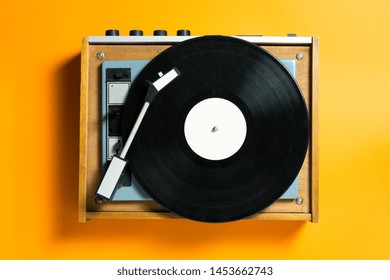 vintage turntable vinyl record player on orange background. retro sound technology to play music