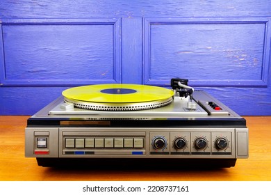 Vintage turntable vinyl record player with yellow vinyl on a table - Shutterstock ID 2208737161