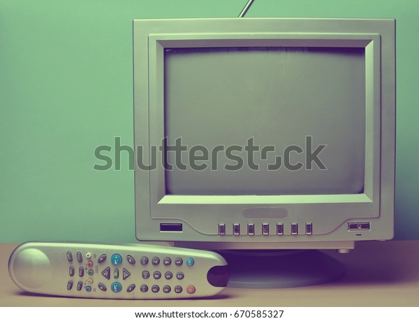 Vintage TV from 80s, remote control on a pastel\
background. Entertainment\
80s.