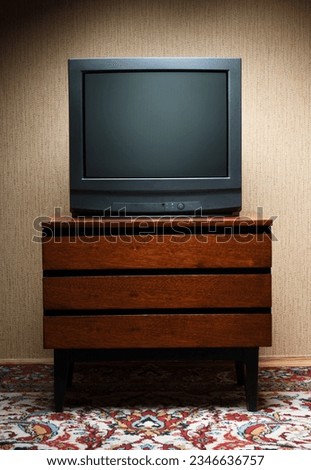 Vintage TV on wooden antique closet, old design in a home.Old black vintage TV.