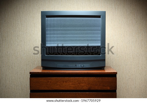 Vintage TV on a\
wooden antique cabinet, old design in the house. Old black vintage\
TV with clutter on the\
screen.