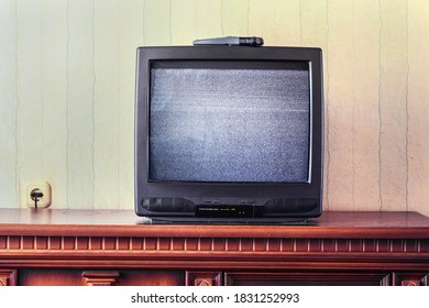 vintage tv screen with glitch static image stands on wooden table in room front view - Powered by Shutterstock