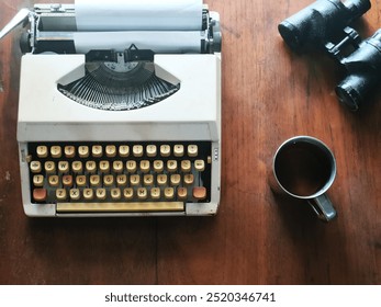 Vintage Typewriter with cup of tea and Binoculars on Wooden Desk - Powered by Shutterstock