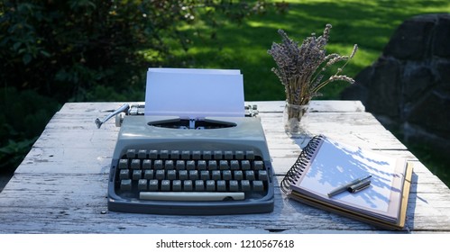 Vintage typewriter, notebook and lavender flovers on white wooden desk in the garden. Perfect pleace for work.
	
