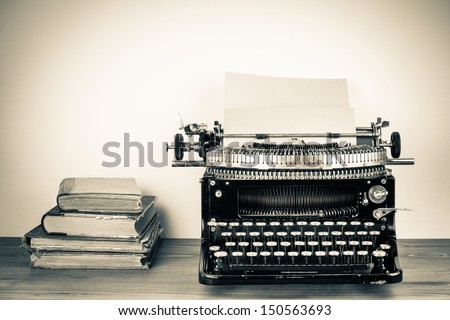 Vintage typewriter, old books on table sepia photo