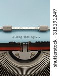 Vintage Typewriter With Phrase "A long time ago" Typed on Blue Paper Vertical Photograph