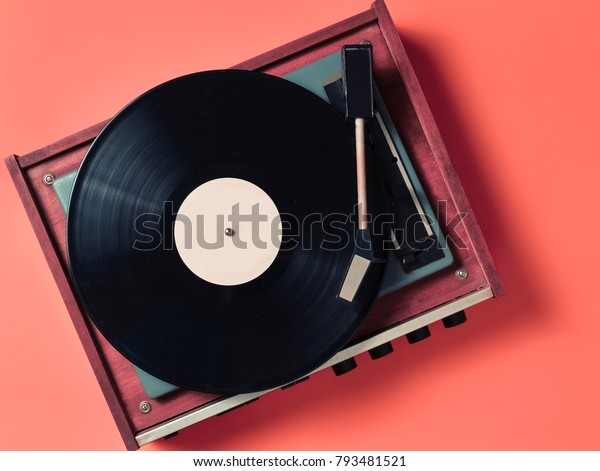 Vintage\
vinyl turntable with vinyl plate on an orange background.\
Entertainment 70s. Listen to music. Top\
view.