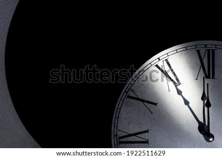 Vintage wall clock with roman numerals showing five minutes to midnight as a symbol for time running out