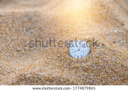 Vintage watch on sand beach with vintage morning warm light, swimming in the time, loosing time, sand watch, outdoor day light