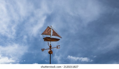 Vintage weather vane in the form of ship on the background with blue dark sky and white clouds, Bulgaria