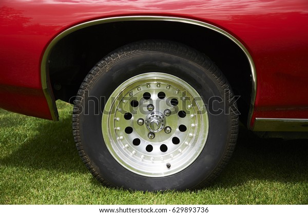 Vintage wheel of classic car on green grass lawn.
Beautiful photo of a stunning retro car. Stylish vehicle. Nostalgia
of past time. Close up.
