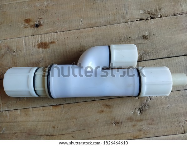 Vintage white\
plastic double-check valve isolated on wooden board background.\
Long valve, non-retun\
valve.