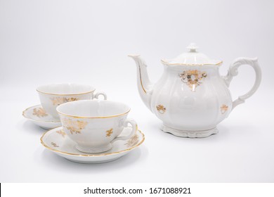 Vintage white teapot with tea cups  with golden rim in classic style isolated on white background