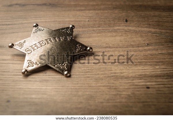 Vintage Wild West Sheriff badge on a rustic\
wood background.