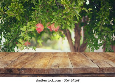 vintage wooden board table in front of dreamy pomegranate tree landscape. retro filtered image
