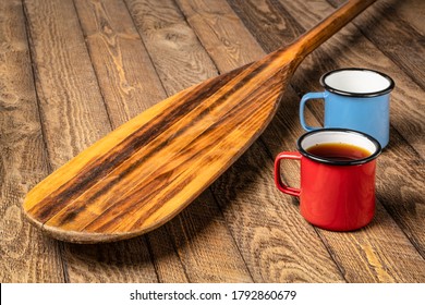 Vintage Wooden Canoe Paddle  On Weathered Wood Picnic Table With Metal Cups Of Tea