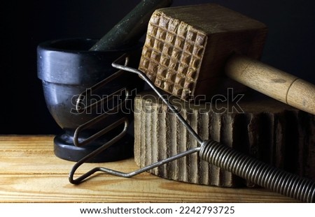 VINTAGE WOODEN MALLET AND METAL MASHER WITH A WOODEN KITCHEN BLOCK AND A BLACK MARBLE PESTLE AND MORTAR