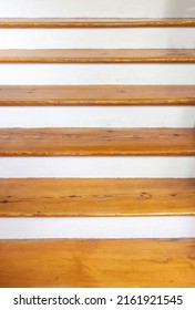 Vintage wooden stair with brown plank tread and white riser. Interior stairway old structure, upstairs direction or wood shelf on white painted wall.