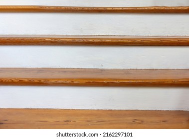 Vintage wooden stair with brown plank tread and white riser. Interior stairway old structure, upstairs direction or wood shelf on white painted wall.