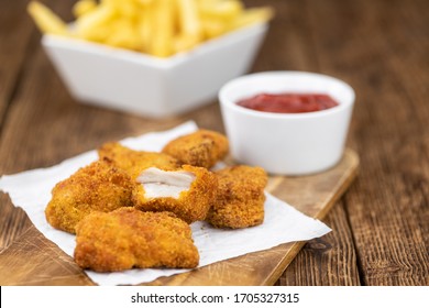 Vintage wooden table with fresh made Chicken Nuggets (close-up shot; selective focus)