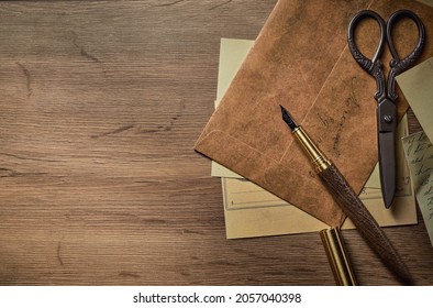 Vintage writing utensils on a wooden table, old watch, papers, letters, envelopes and scissors - Shutterstock ID 2057040398