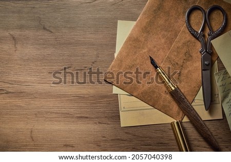 Vintage writing utensils on a wooden table, old watch, papers, letters, envelopes and scissors