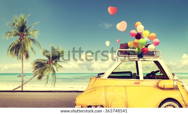 Vintage\
yellow car with heart colorful balloon on beach blue sky - concept\
of love in summer and wedding. Honeymoon\
trip