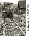 Vintage-style image of an authentic old mining ore cart and tracks in a historical western American ghost town - monotone tint and focus point on cart.