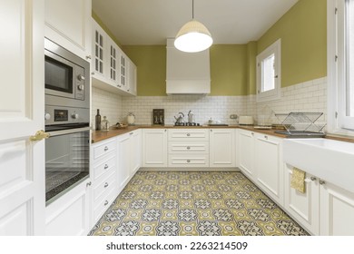 Vintage-style kitchen furnished in a u-shaped white lacquered wood with wooden countertop, white tiles and hydraulic tile floor
