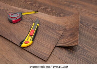 Vinyl Flooring Installation. Easy Installation And Cutting With A Knife, Master Cuts Vinyl Plank Before Installation, Brown Heated Floor. Copy Space