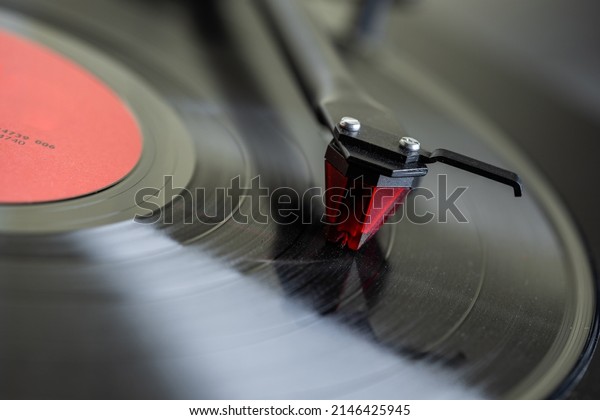 Vinyl player.\
The tonearm\
with the stylus is mounted on a black spinning vinyl record. Red\
cartridge