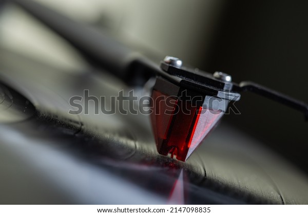 Vinyl player.\
The tonearm\
with the stylus is mounted on a black spinning vinyl record. Red\
cartridge