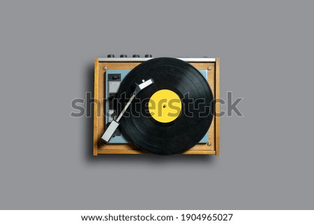 Vinyl record player with yellow label on a gray background. Modern phonograph record concept in trendy colors