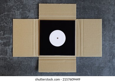 Vinyl record single packed in cardboard mailer shipping box.