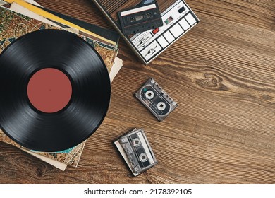 Vinyl records, cassette tapes and cassette recorder on wooden table. Retro music style. 80s music party. Vintage style. Analog equipment. Stereo sound. Back to the past