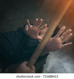 Violent Man Carries A Wood Stick And Attempts To Attack An Scared Woman That  Fall Down On The Floor - Concept Photo Of Physical Abuse
