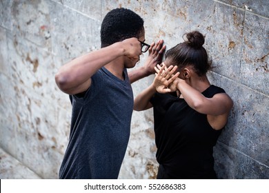 Violent young man threatening his girlfriend with his fist outdoors