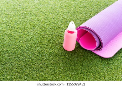 Violet female carpet and Pink bottle water for doing yoga on open air space terrace green grass. Fuchsia rug. Workout gym Healthcare health active life concept. Copy space - Powered by Shutterstock