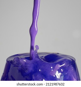 Violet liquid poured into glass with splash
