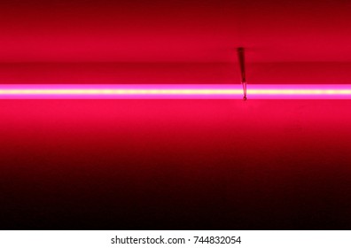 Violet Neon Tube Light Glowing On A Red Background Wall