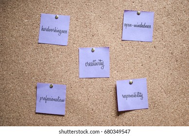 Violet note on the cork board with handwritten words hardworkingness, open-mindedness, creativity, responsibility, professionalism 