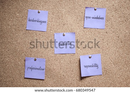 Violet note on the cork board with handwritten words hardworkingness, open-mindedness, creativity, responsibility, professionalism 