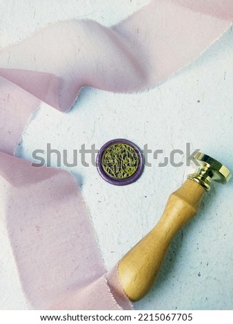 Violet purple with gold ink two koi fish swimming wax stamp or wax seal coin and a wooden wax stamp with pink ribbon on a white background