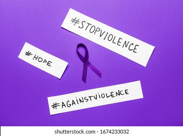 Violet ribbon with different hashtags on color background. Domestic violence concept