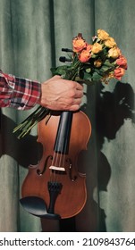Violin and a bouquet of flowers in hand on a green cloth. Music as a gift. Front view.