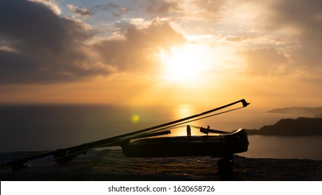 Violin with bow by the sea at sunset
