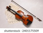 Violin, bow and music sheets on grey marble table, top view