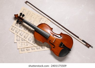 Violin, bow and music sheets on grey marble table, top view - Powered by Shutterstock