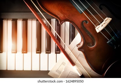 Violin bow and sheet music on piano keys. Concept of interpretation of piano music and string instruments. Top view. Horizontal composition.