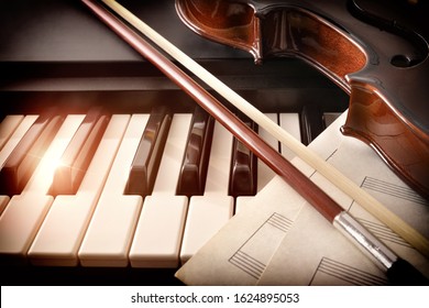 Violin bow and sheet music on piano keys. Concept of interpretation of piano music and string instruments. Front view. Horizontal composition. - Powered by Shutterstock